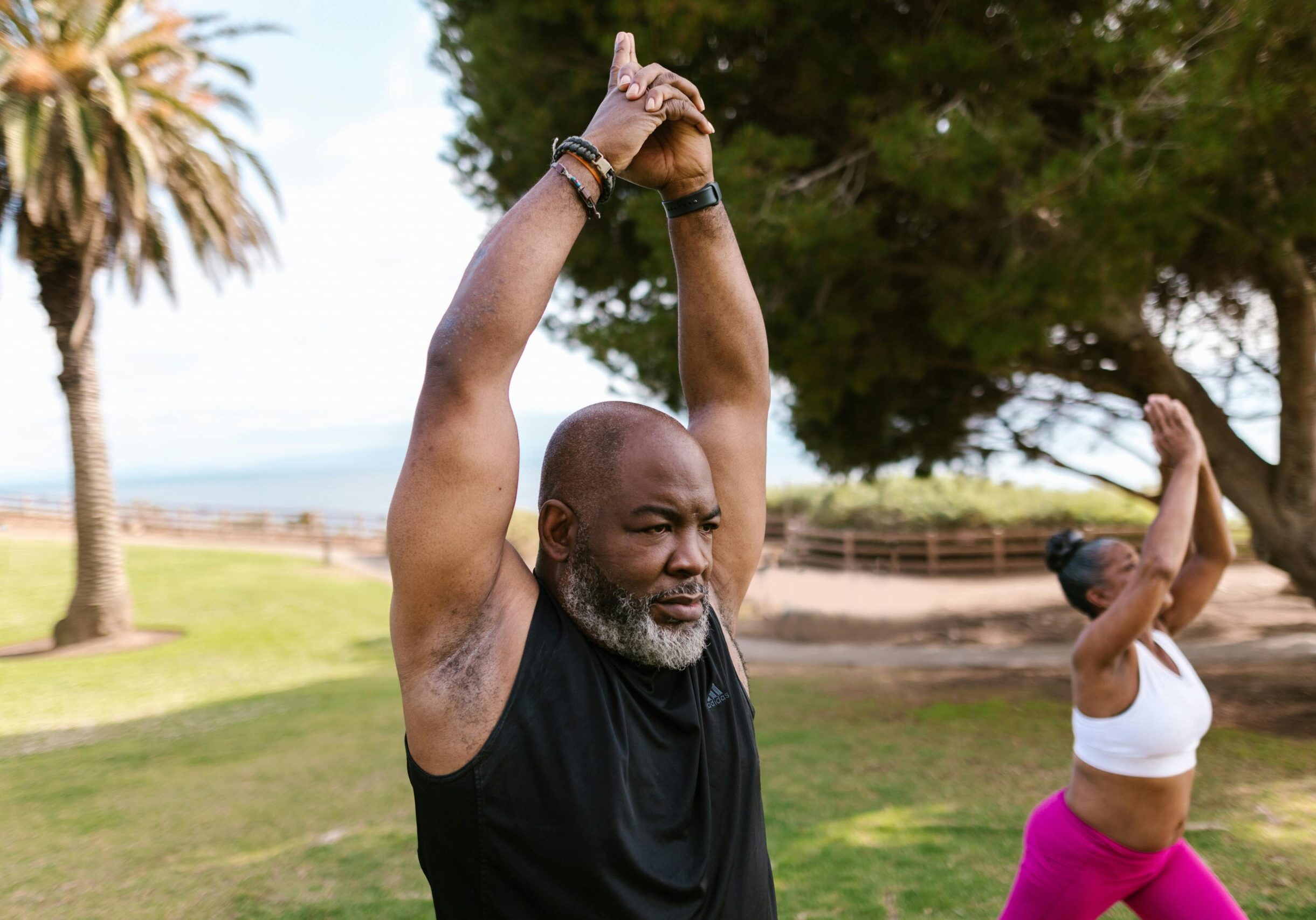 man and woman practicing yoga in park