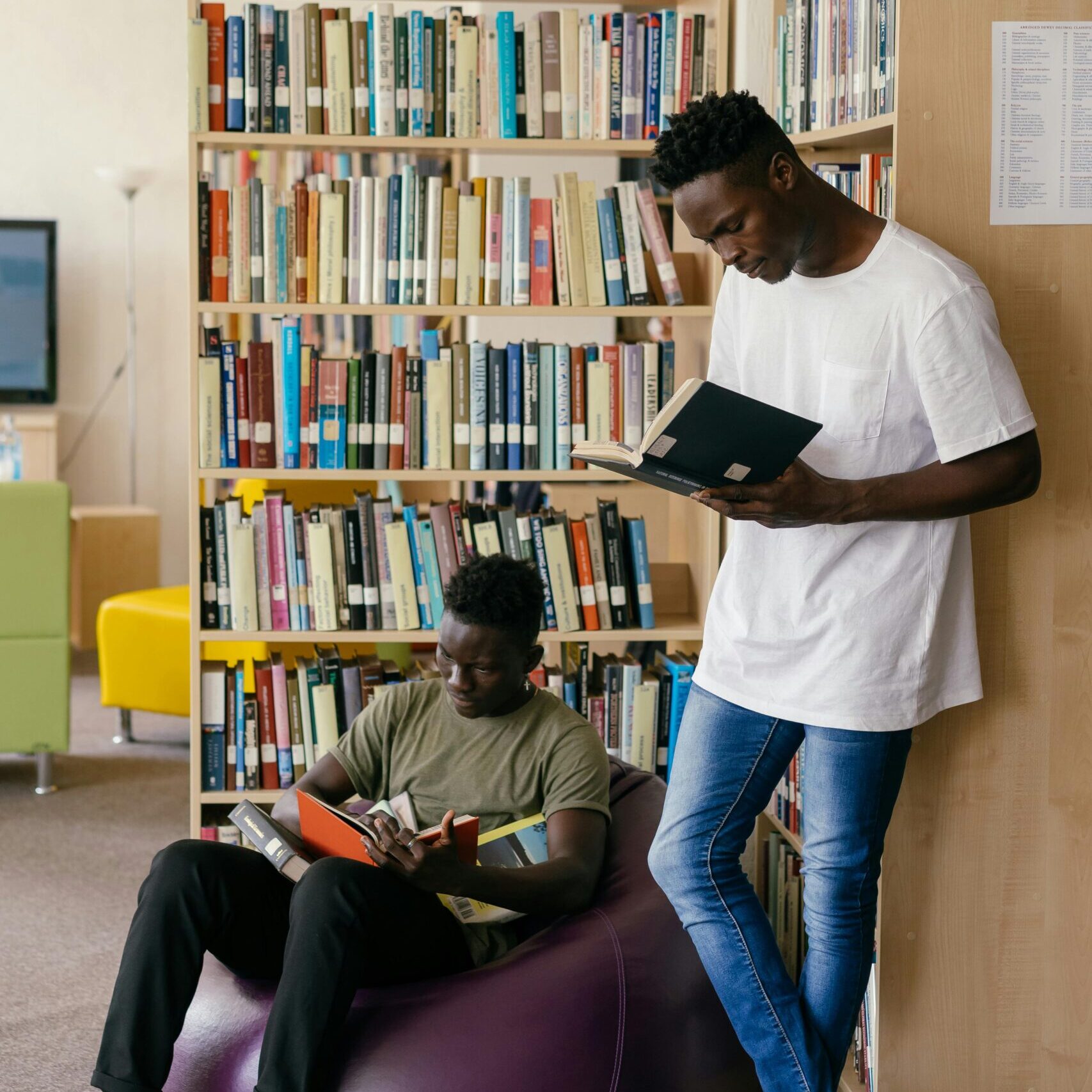 Two adult students are reading in library.