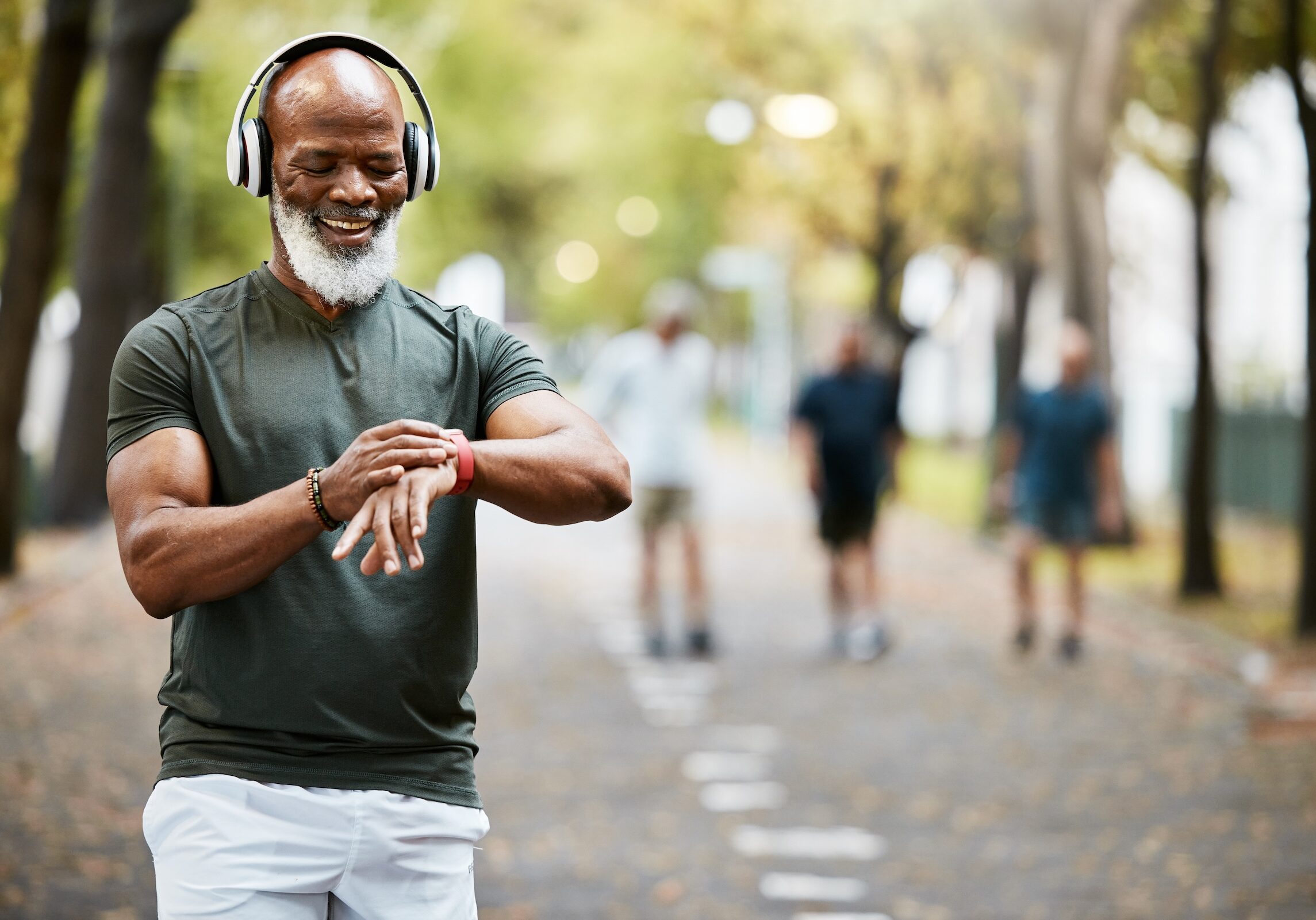 mature black man looking at his watch while out for a fitness run in the park. Workout, wellness and training with a senior male athlete or runner tracking his health