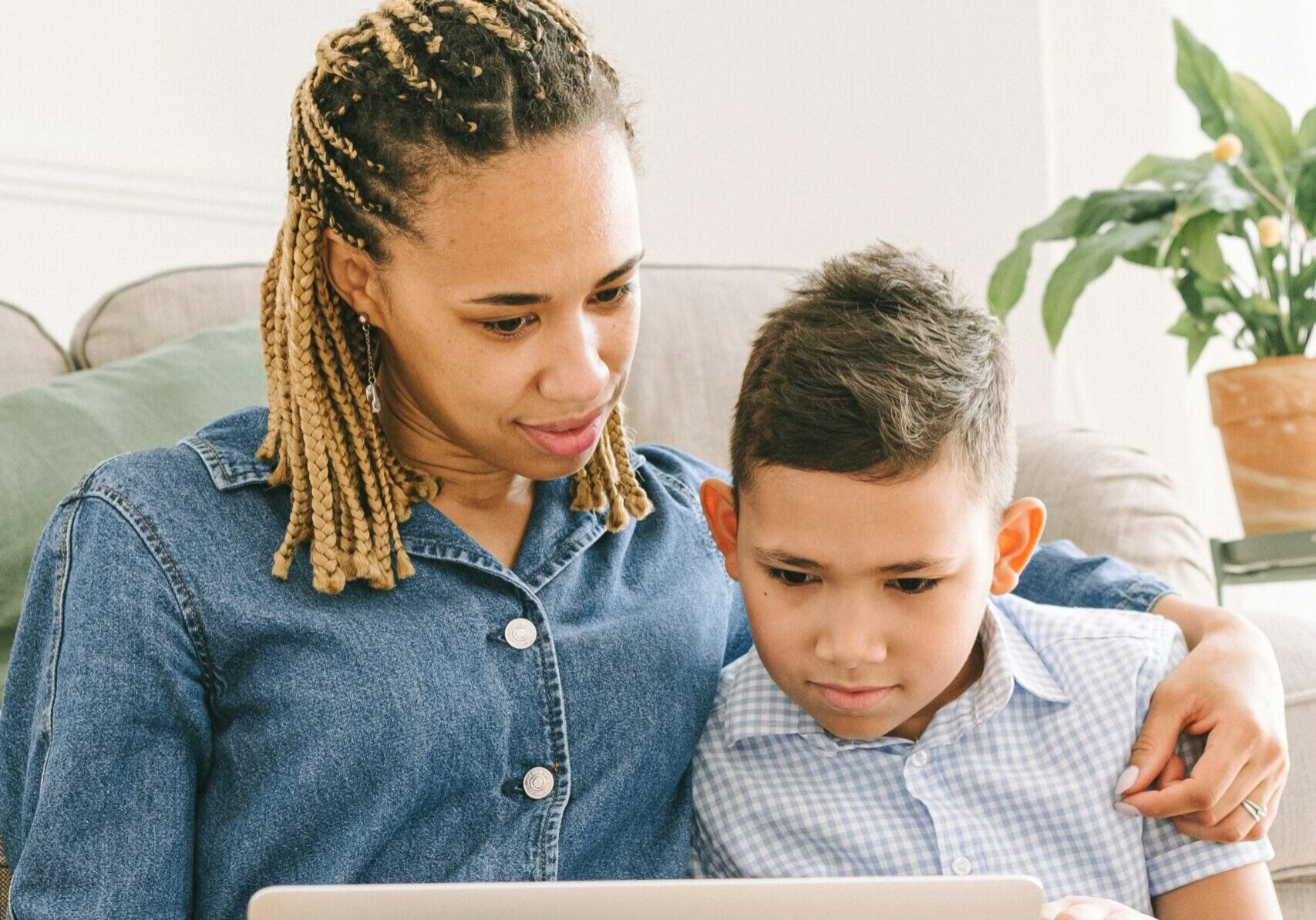 A mom and her son watch are looking at a laptop screen together.